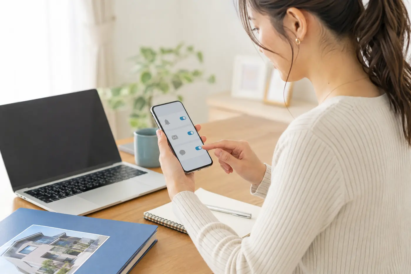 不動産査定の連絡方法をスマートフォンで確認する女性